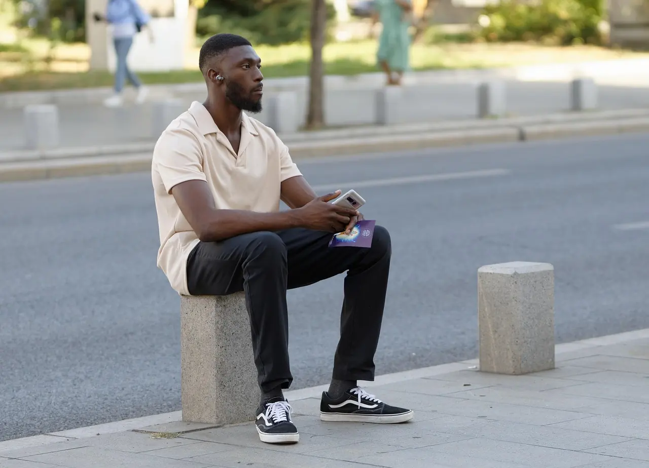 A man checking his phone on a city street abroad